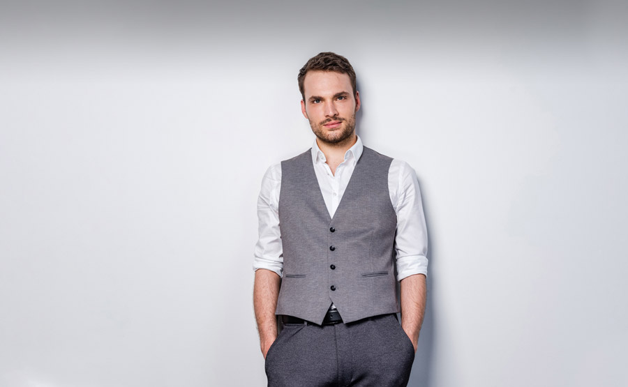 Max Dollinger – Lehnt an der Wand in Anzug-Weste etc.