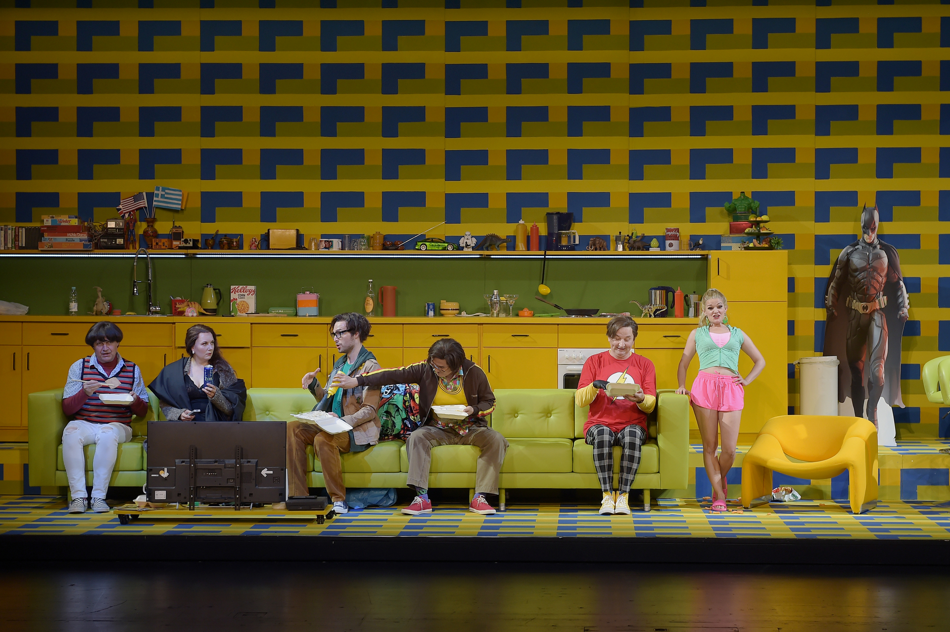 Max Dollinger, Pauliina Linnosaari, Liudmila Lokaichuk sitzen auf einer langen grünen Couch in einem farbigen Wohnzimmer, Ariadne auf Naxos Bühnenfoto des Saarländischen Staatstheater Saabrücken
